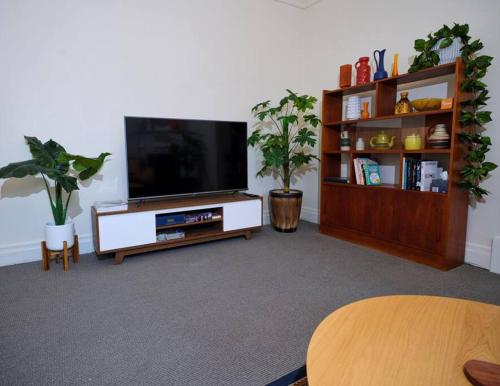 ein Wohnzimmer mit einem Flachbildfernseher auf einem Entertainment-Center in der Unterkunft Beautiful Cottage in cosmopolitan Norwood in Kensington and Norwood