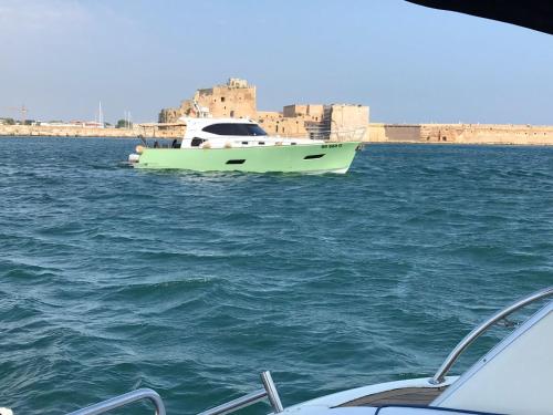 un barco verde en el agua junto a una ciudad en MANIMAN, en Taranto