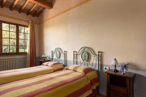 a bedroom with two beds and a window at Fattoria la Gigliola - La Limonaia in Montespertoli