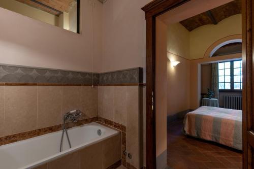a bathroom with a bath tub and a bed at Fattoria la Gigliola - La Limonaia in Montespertoli