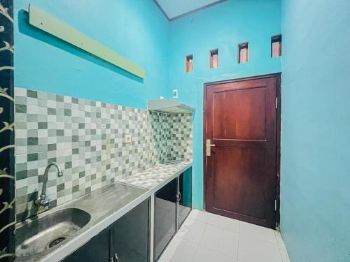 a bathroom with a sink and a brown door at RedDoorz Syariah near Sunrise Mall Mojokerto in Mojokerto