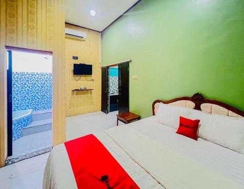a bedroom with a bed with a red pillow on it at RedDoorz Syariah near Sunrise Mall Mojokerto in Mojokerto