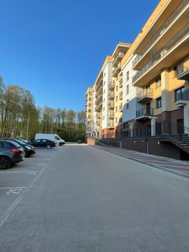een lege parkeerplaats met auto's naast gebouwen bij NaturaApart bezpłatny parking in Ostrołęka