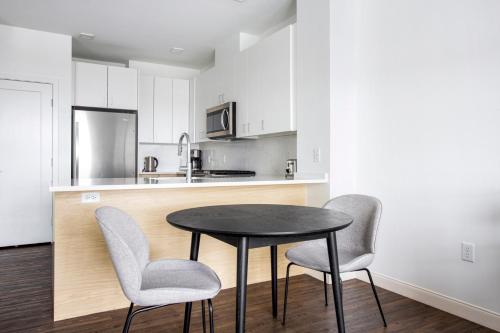a kitchen with a table and two chairs and a counter at 1BR w Gym WD Steps from Newtonville Train BOS-354 in Newton
