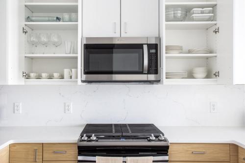 a microwave above a stove in a kitchen at 1BR w Gym WD Steps from Newtonville Train BOS-354 in Newton