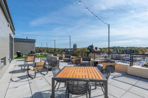 a patio with a wooden table and chairs on a roof at 1BR w Gym WD Steps from Newtonville Train BOS-354 in Newton