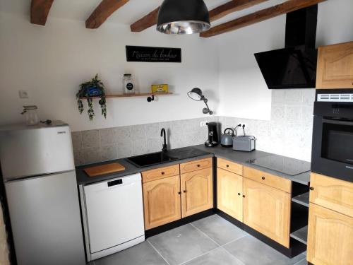 uma cozinha com armários de madeira e um frigorífico branco em Maison de charme em Ligueil