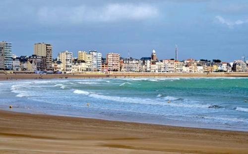 a view of a beach with a city in the background at Remblai des Sables d'Olonne - 2 chambres - parking et piscine in Les Sables-dʼOlonne