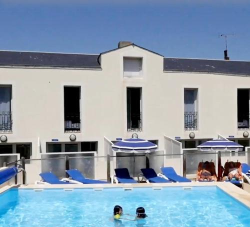 a swimming pool with blue chairs and umbrellas at Sur le remblai des Sables comprenant 2 ch parking et piscine in Les Sables-dʼOlonne