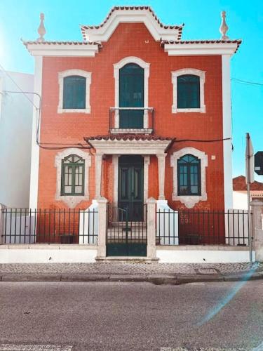 a red house with a black fence in front of it at Jugendstil Villa - 2 min zum Meer in Figueira da Foz