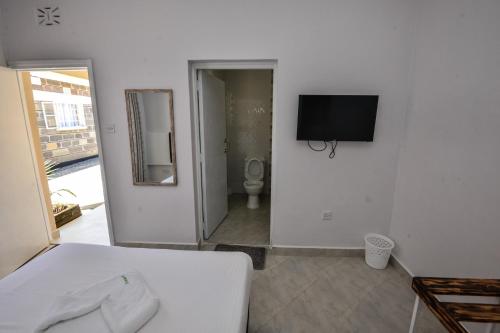 ein Schlafzimmer mit einem Bett und einem TV an der Wand in der Unterkunft Eldorado Rustic Hotel in Nakuru