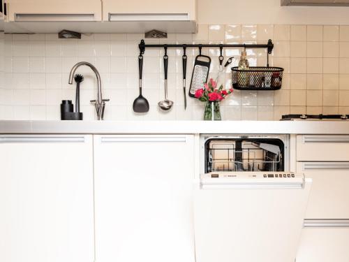 a kitchen with white cabinets and utensils on the wall at Stayatsas Tiny House Julia in de bossen op de Veluwe! in Epe