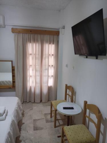 a room with a bed and a table and a television at Kissandros Hotel in Agia Galini