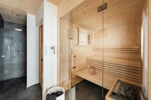 a bathroom with a sauna with a glass wall at Gähwindehof Mountain Ranch Resort in Oberstaufen