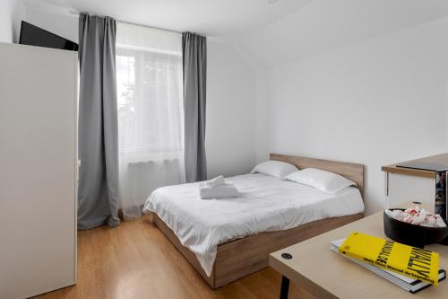 um quarto com uma cama, uma secretária e uma janela em DD Boutique Apartments em Cluj-Napoca