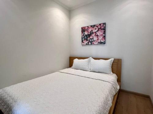 1 dormitorio con 1 cama con sábanas blancas y una pintura en la pared en Vinhomes Royal City 2 Bedroom!, en Hanói