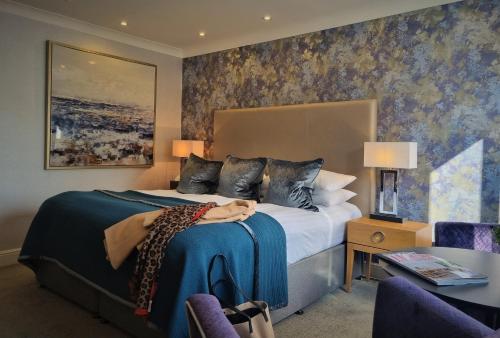 a bedroom with a large bed with a blue blanket at Rowhill Grange Hotel & Utopia Spa in Dartford