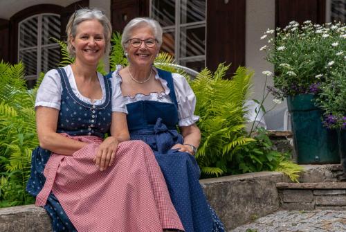 two older women sitting next to each other in a garden at Seehotel Enzian in Weissensee