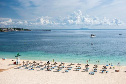 a beach with umbrellas and people swimming in the water at Zel Mallorca in Palmanova
