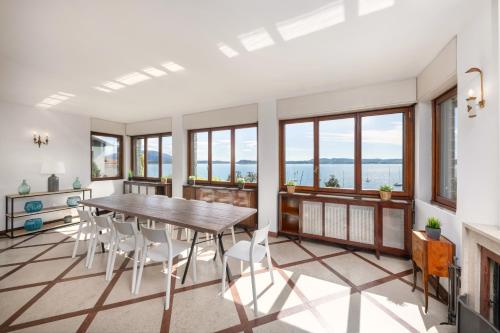 a dining room with a table and chairs and windows at Villa Lexa by Casa da Suite in Lesa