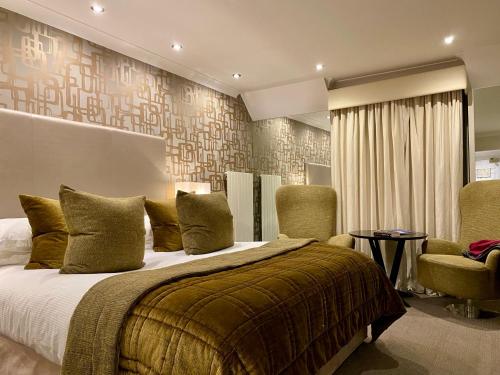 a bedroom with a large bed and two chairs at Rowhill Grange Hotel & Utopia Spa in Dartford