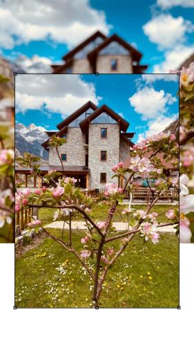 a large stone house with pink flowers in front of it at Guesthouse Prrockaj Theth in Theth