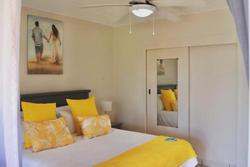 a bedroom with a bed with yellow pillows at Laguna la Crete 66 in Uvongo Beach