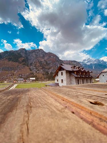 a dirt road in front of a building with mountains in the background at Guesthouse Prrockaj Theth in Theth