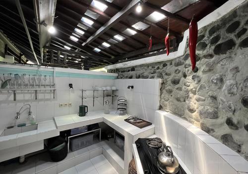 a kitchen with white counters and a stone wall at The Mahogany Villa Ubud in Tegalalang