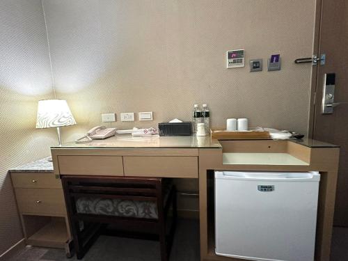 a desk in a room with a lamp and a refrigerator at 銀座飯店Ginza Hotel in Taipei