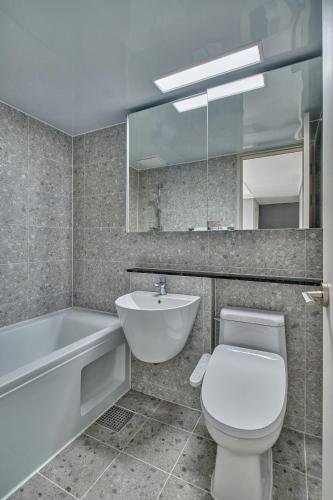 a bathroom with a toilet and a tub and a sink at Gangneung Chonpines Ocean Suites Hotel in Gangneung