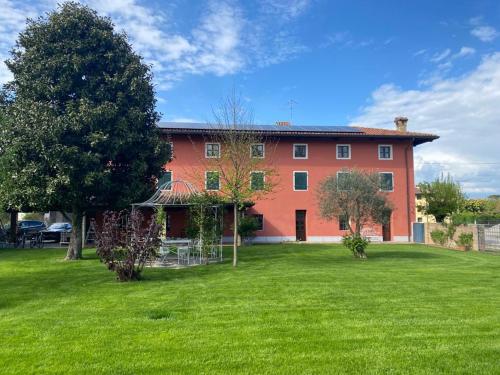 une grande maison rouge avec une pelouse verte en face de celle-ci dans l'établissement Fiori Di Maggio, à Muscletto