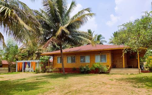 a house with a palm tree in front of it at Brahmi Resort in Bangalore