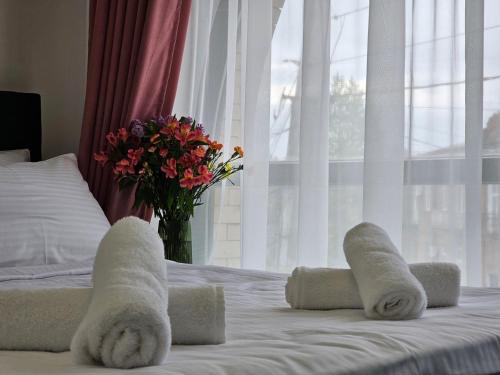 a bed with towels and a vase of flowers on it at Boutique Hotel Honey in Kutaisi