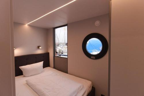 a small bedroom with a bed and a window at Hausboot Fjord Meeresbrise mit Dachterrasse in Flensburg in Flensburg
