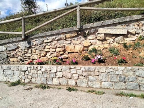 a stone retaining wall with flowers and a fence at CASA TABLADO HELENA in Belmonte de Miranda