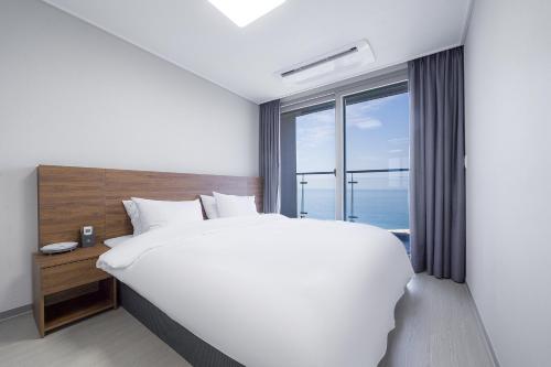a bedroom with a large bed and a large window at Gangneung Chonpines Ocean Suites Hotel in Gangneung