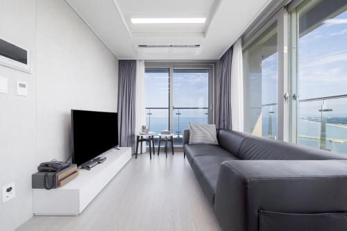 a living room with a couch and a tv at Gangneung Chonpines Ocean Suites Hotel in Gangneung