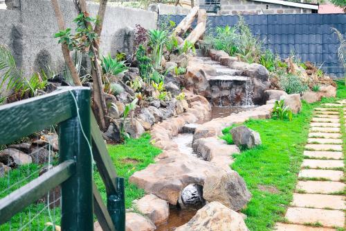 a garden with a pond and rocks and a fence at Eldorado Rustic Hotel in Nakuru