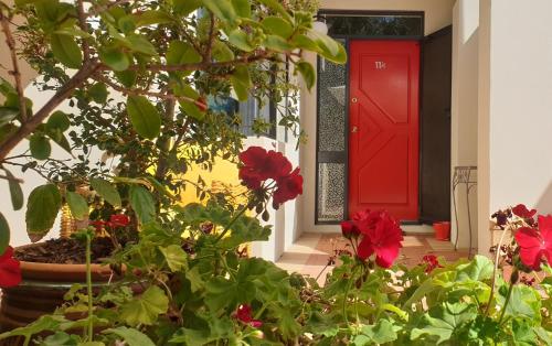 a red door with red flowers in front of a house at Como Executive Apartment in Perth