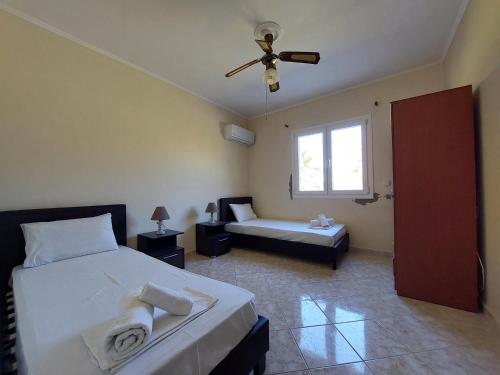 um quarto com 2 camas e uma ventoinha de tecto em Lakkopetra Beach House em Kato Achaia