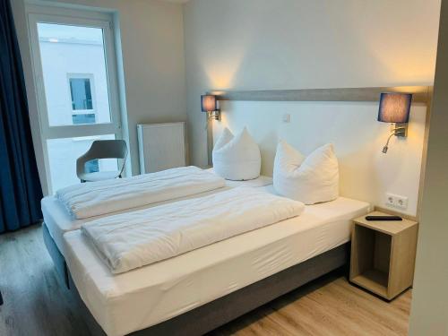 ein Schlafzimmer mit einem großen Bett mit weißer Bettwäsche und Kissen in der Unterkunft Fewo Frida BOW 321 in Kappeln