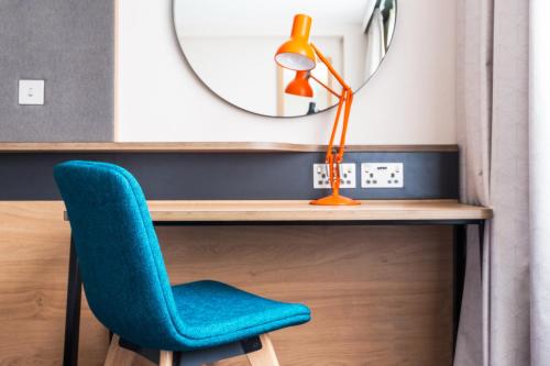 a desk with a blue chair and a lamp at Holiday Inn Coventry M6, J2 by IHG in Coventry