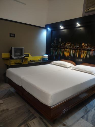 a large white bed in a room with a wall at Krishna Lodge in Tiruchchirāppalli