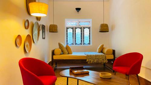 ein Wohnzimmer mit einem Sofa und zwei roten Stühlen in der Unterkunft Villa Pont Bleu in Canacona