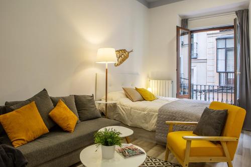- un salon avec un canapé et un lit dans l'établissement Apartamento coqueto en la calle Huertas, à Madrid