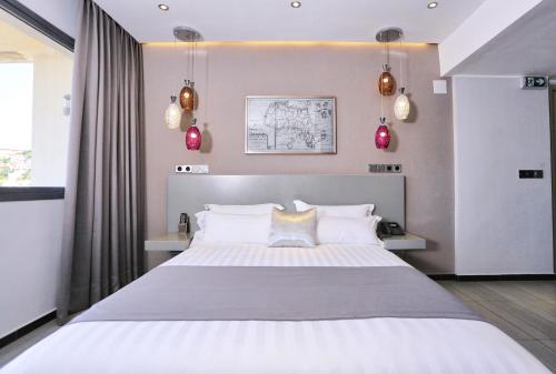 - une chambre avec un grand lit blanc aux murs roses dans l'établissement Le Fred, à Antananarivo