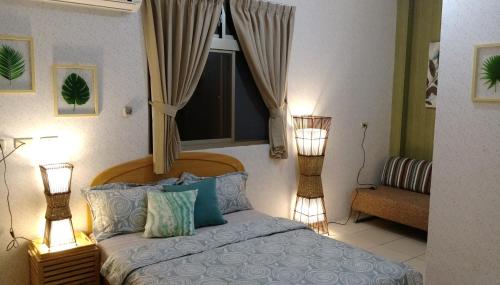 a bedroom with a bed with a window and two lamps at Song Lin Homestay in Dongshan