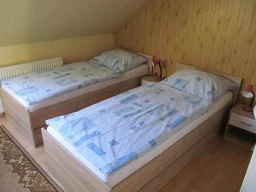 two twin beds in a room with wooden walls at A+S Penzion Podzamok in Spišské Podhradie