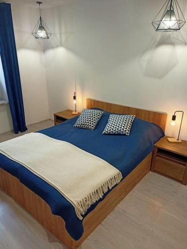 um quarto com uma cama azul com duas mesas de cabeceira em Apartament w centrum miasta przy parku i jeziorze em Szczecinek